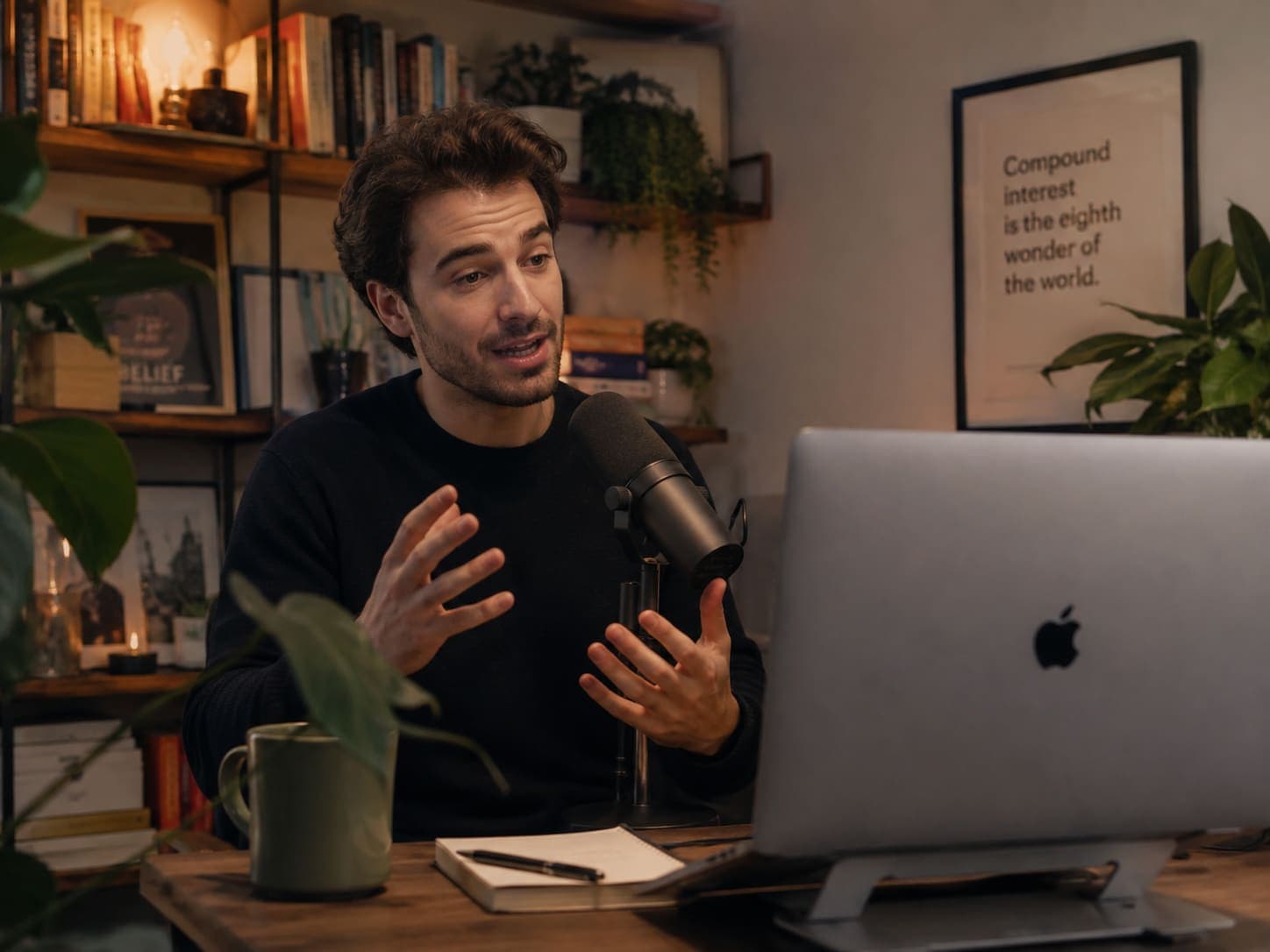 A creator speaking into a microphone at a desk with a laptop.